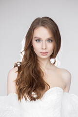 Portrait of a charming young woman in a luxurious white dress on a black background. A bride in a wedding dress, a happy smile and a portrait.