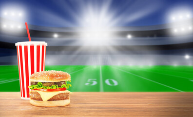 Burger and drinks on a wooden table . TV broadcast of American football background. Sport bar...