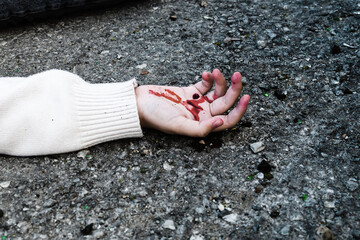 a man's hand is covered in blood lying on the asphalt on the road