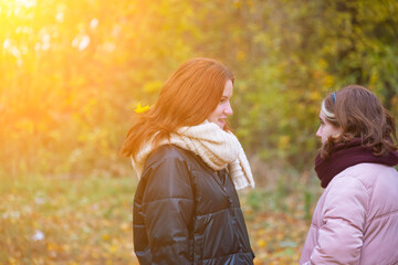 two red-haired girls on the background of autumn nature talk to each other, the concept of human emotions