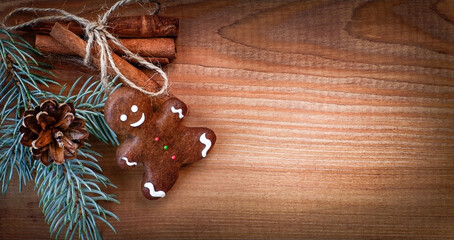 gingerbread man, cinnamon and a branch of a Christmas tree on a wooden background
