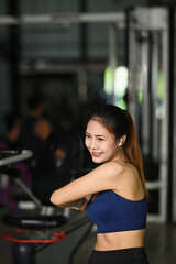Fototapeta na wymiar Smiling young woman warming up before workout in gym.
