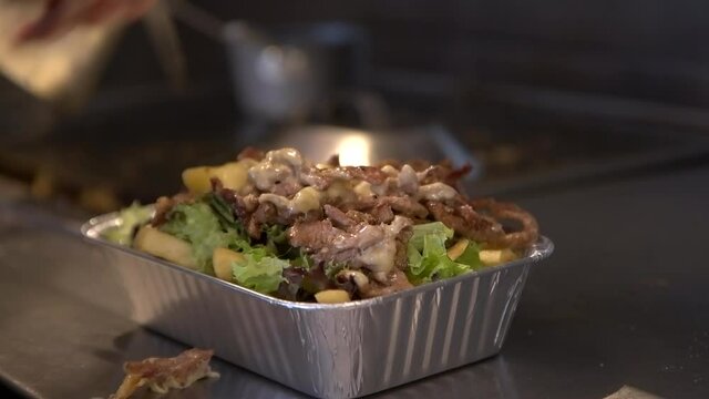 Chef Puts Cooked Meat At The Top In Dutch Street Food Of Kapsalon. medium shot 