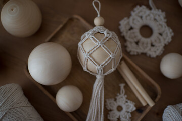 Christmas ball in the macrame technique, materials for creativity on a wooden table.