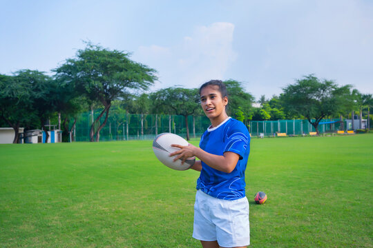 Young athlete girl holding the rugby ball and looking away on the field