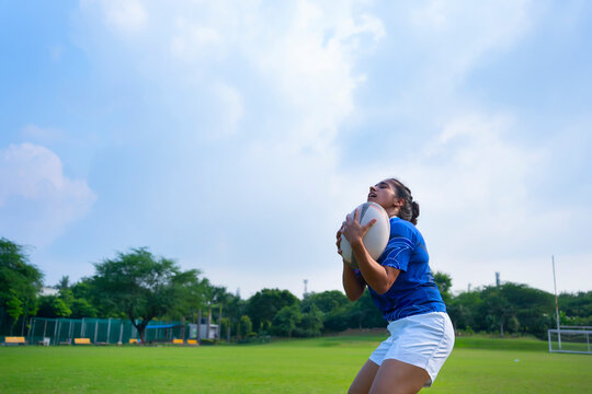 Young athlete girl practicing rugby on the sports field