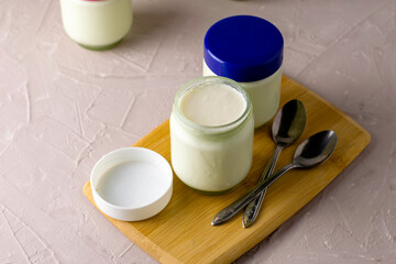 jars of homemade yogurt and spoons on a cutting board