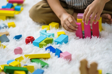 Children play wooden blocks with geometric shapes.
