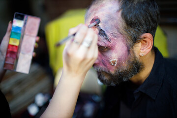 Zombie male makeup applying for halloween concept. Make up with brush and paint skin and blood face
