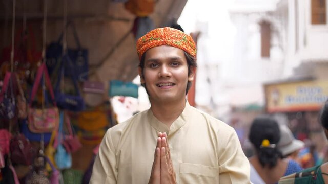 A young man wearing a traditional Rajasthani Pagdi doing a Namaste gesture. Pushkar market in the daytime - business  daily lifestyle