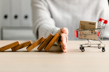 Women's hand protect falling collapse wooden block dominoes effect continuous toppled cart shopping, preventing risk and crisis business, management strategy e-commerce, insurance concept.