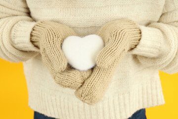 Girl holds decorative snow heart on yellow background