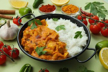 Chicken tikka with ingredients on green background