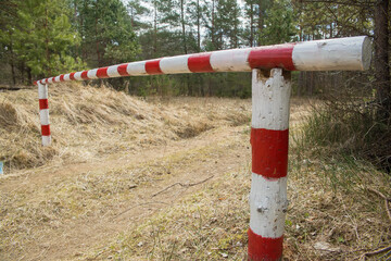 A red and white roadblock closes the forest road.