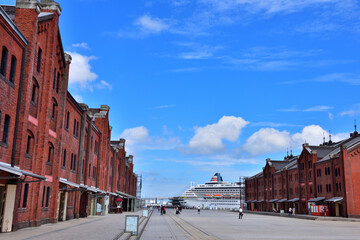 Obraz premium 青空に浮かぶ白い雲と赤レンガ倉庫と豪華客船