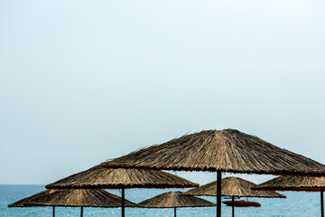 Large straw umbrellas on the beach against the background of the sea and sky.