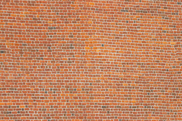 A wide brick blank wall of an old building. Uneven brickwork on a large wall.