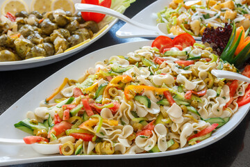 Mix of cucumbers, bell peppers and pasta on a large plate.