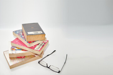 stacks of books on white background high angle view with reading glasses copy space