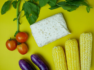 the concept of healthy food consists of eggplant, spinach, tomatoes, and corn. vegetarian food. isolated on a yellow background