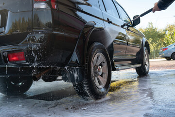 self-service car wash, black jeep is washed with foam and water