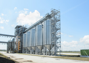 Modern commercial grain or seed silos in rural landscape. Metal grain elevator in agricultural zone
