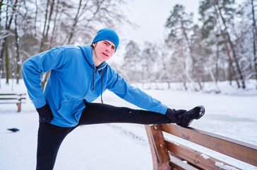 Healthy lifestyle. Young strong man is exercising at snowy park.
