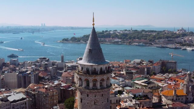 Galata Tower of Istanbul with majestic cityscape view and boats in water, aerial orbit view