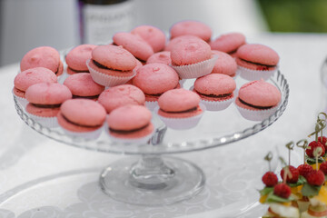 Obraz na płótnie Canvas pink macaroni cookies on a glass tray. Street, wedding reception.