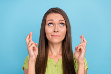 Photo of young worried woman hold fingers crossed look empty space isolated on pastel blue color...