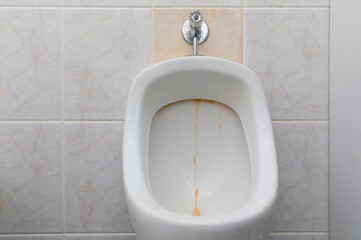 urinal with traces of limescale and rust, tile toilet before cleaning