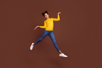 Fototapeta na wymiar Full size photo of active preteen girl jump wear shirt jeans shoes isolated on brown color background