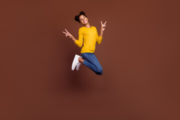 Full body photo of teen girl jump show v-sign wear pullover jeans sneakers isolated on brown color background