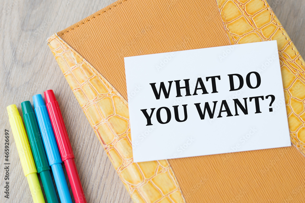 Poster text what do you want on card on office desk, next to a yellow notepad and colored markers