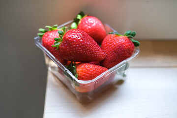 Fresh red strawberries in plastic container box on wood table