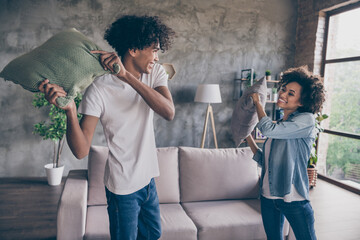 Photo of happy positive dark skin wife husband play pillow fight smile indoors inside house home apartment