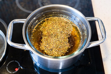 tincture from medicinal herbs in water bath on ceramic hob at home kitchen