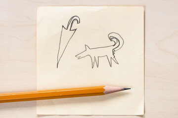 hand drawn sketch of dog and umbrella and black pencil close up on sheet of paper on light brown table