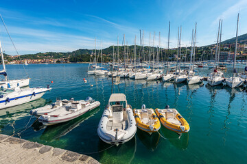 Fototapeta premium Port of the small Lerici town with many boats moored. Tourist resort on the coast of Gulf of La Spezia, Mediterranean sea, Liguria, Italy, Southern Europe. On the left the small village of San Terenzo