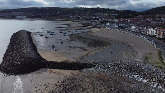 North Wales seaside town coastline resort hotels harbour breakwater aerial view orbit right