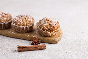 Homemade freshly baked pumpkin muffins with oatmeal and nuts on beige textured background