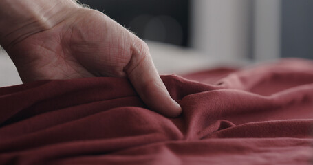 man touching red cotton clothes closeup
