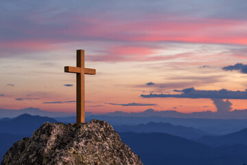 Silhouettes of crucifix symbol on top rock mountain with bright sunbeam on the colorful sky...