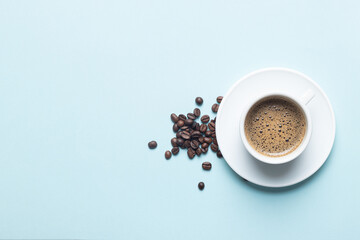 White coffee cup with coffee beans isolated  on light blue background with copy space.