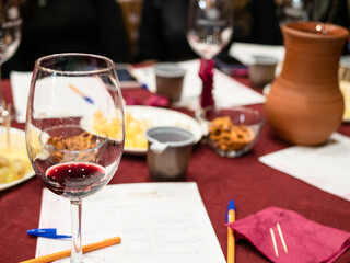 red grape wine tasting - wineglass with tested wine and written notes on table