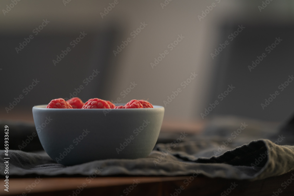 Wall mural yogurt with fresh raspberries in blue ceramic bowl on walnut table with copy space