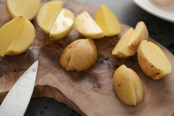 Raw washed and chopped baby potatoes ready to cook on olive wood board