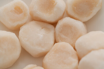 Fototapeta na wymiar closeup of frozen scallops in white bowl on walnut table for defrosting