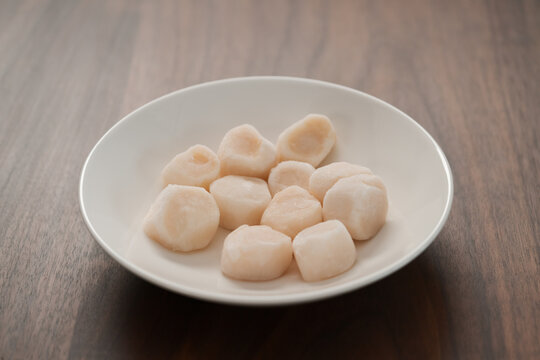 Frozen Scallops In White Bowl On Walnut Table For Defrosting