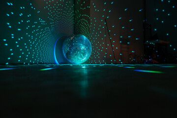 Disco ball reflecting blue and green light in a dark hall for discos.  Disco on the floor. Copy...